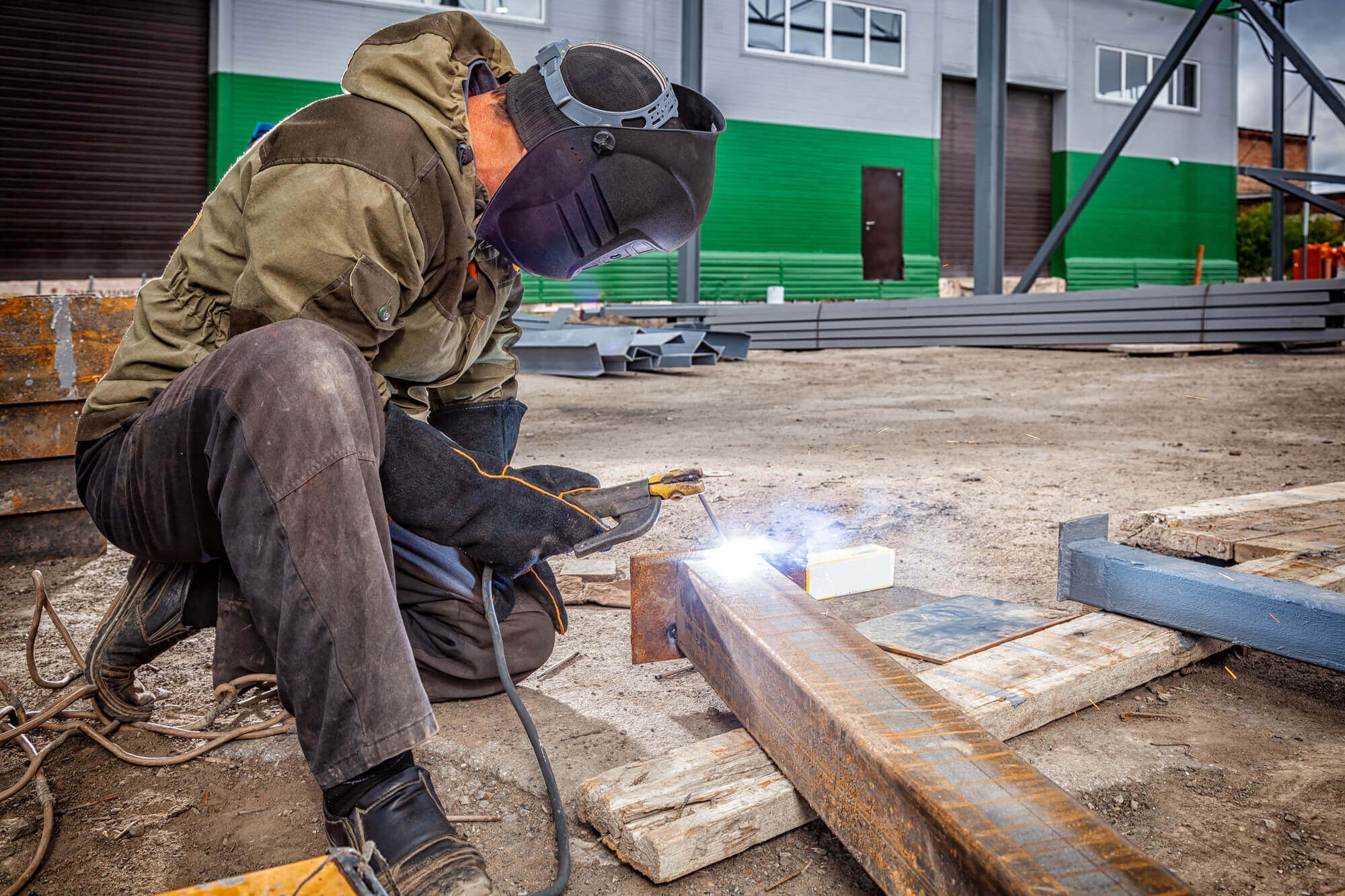 A young man welder in brown uniform, welding mask